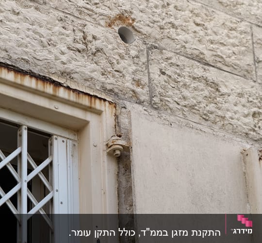 חור בקיר ליד חלון עם סורג מתכת